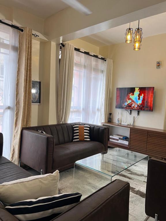 a living room with a couch and a glass table at beautifully furnished one bedroom apartment in vok off nyali road in Mombasa