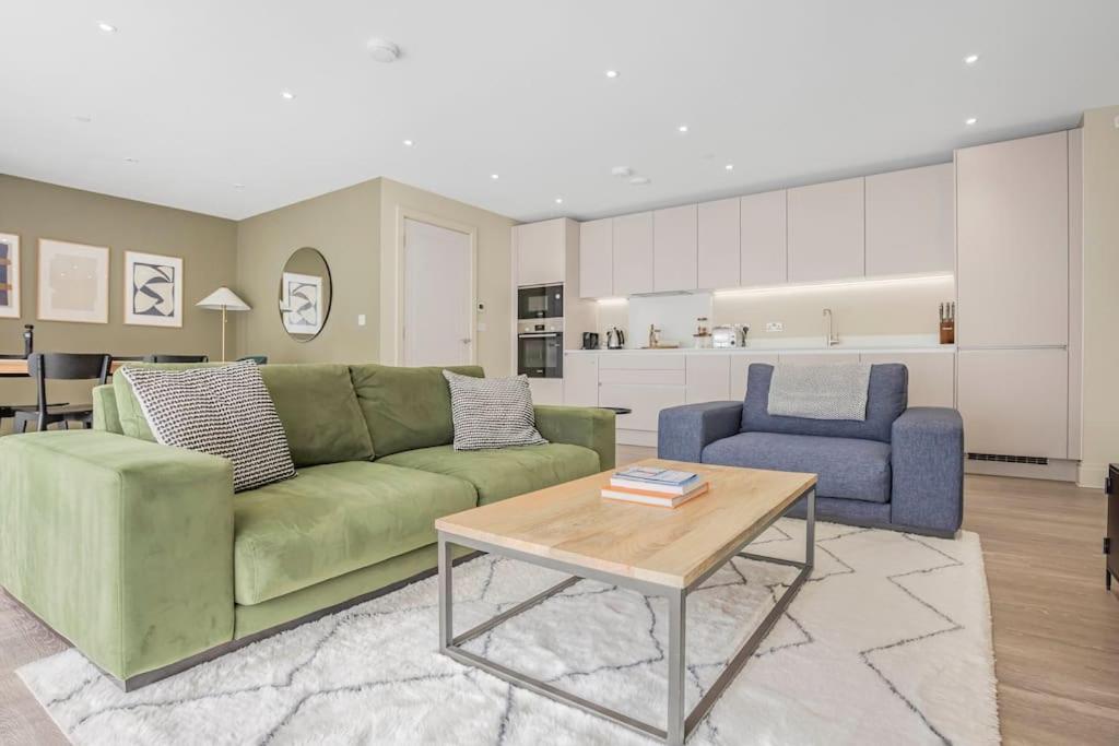 a living room with a green couch and a table at Apartment by the beach in Rest Bay, Porthcawl in Porthcawl