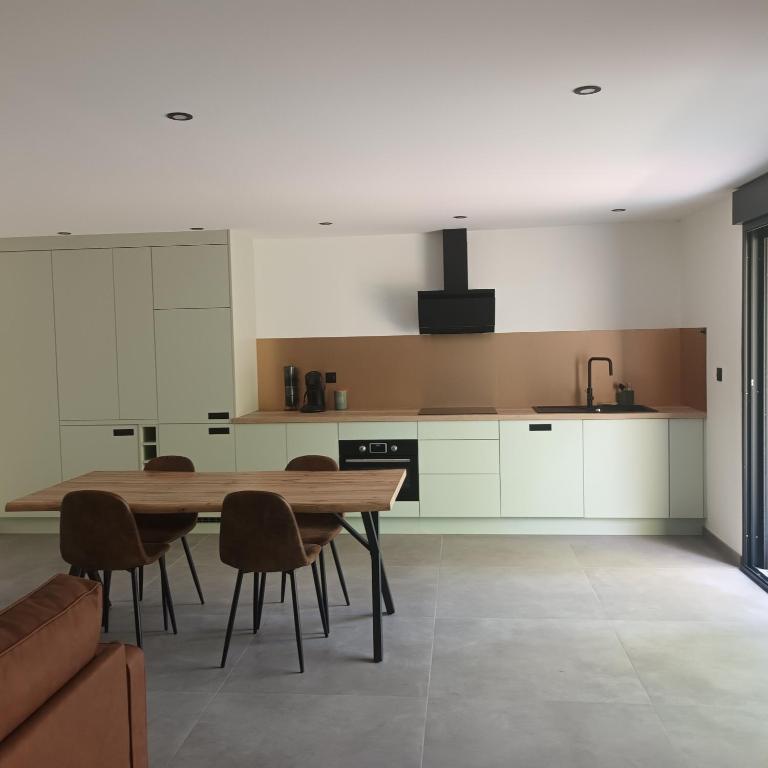 une cuisine avec une table en bois et quelques chaises dans l'établissement Loft du Bugey, à Loyettes