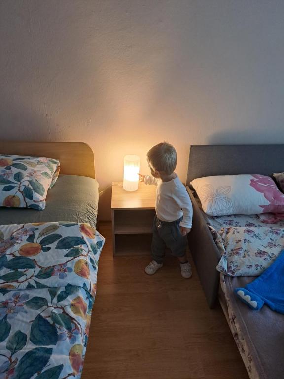 Un niño pequeño mirando una luz en una habitación de hotel. en LevskiG Studio 10 min from Sofia Airport and city centre, en Sofía