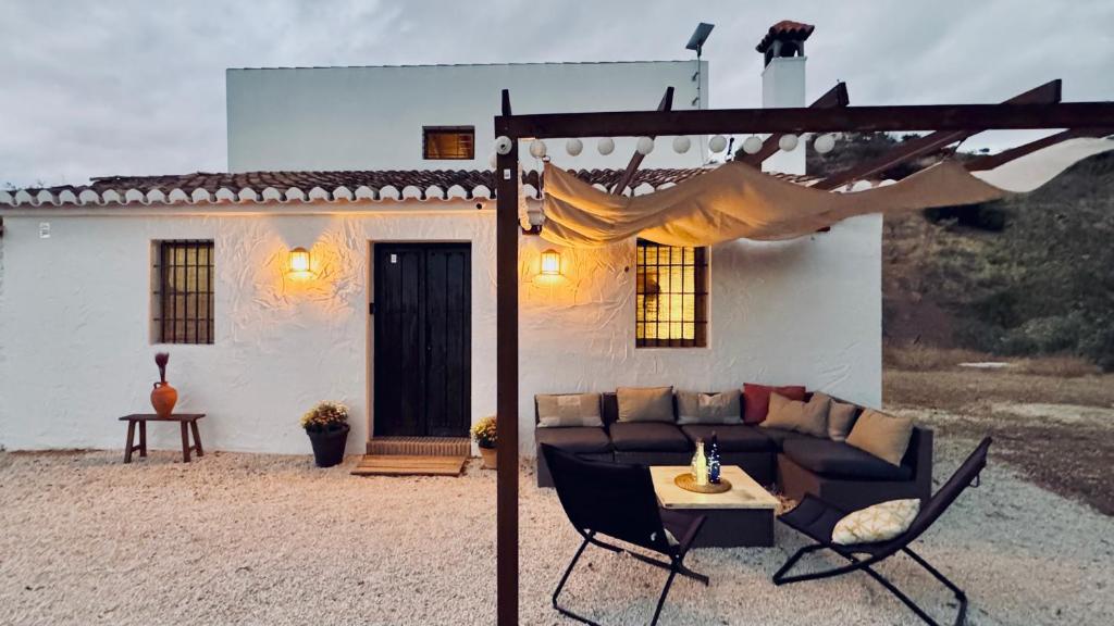 a couch and chairs in front of a house at Los Campos Casa Rural in Almogía