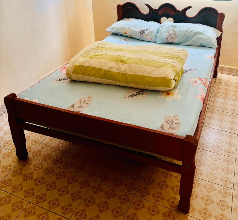 a bed with a wooden frame with a yellow blanket on it at Enchanting Oasis in Embu