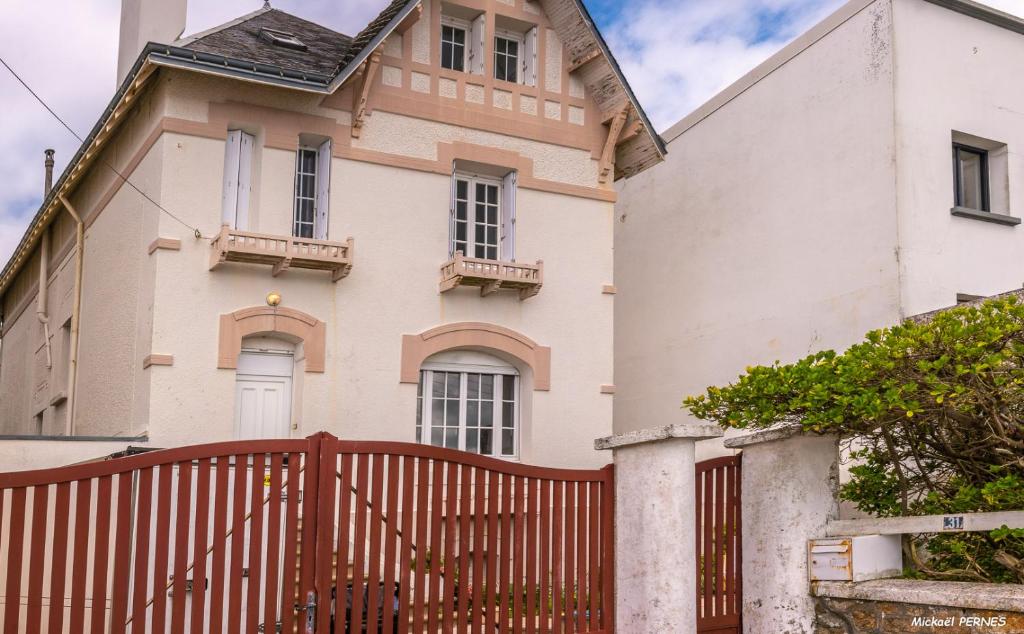 a house with a wooden fence in front of it at RÉF 407 - LARMOR PLAGE Maison de famille pleine vue mer in Larmor-Plage