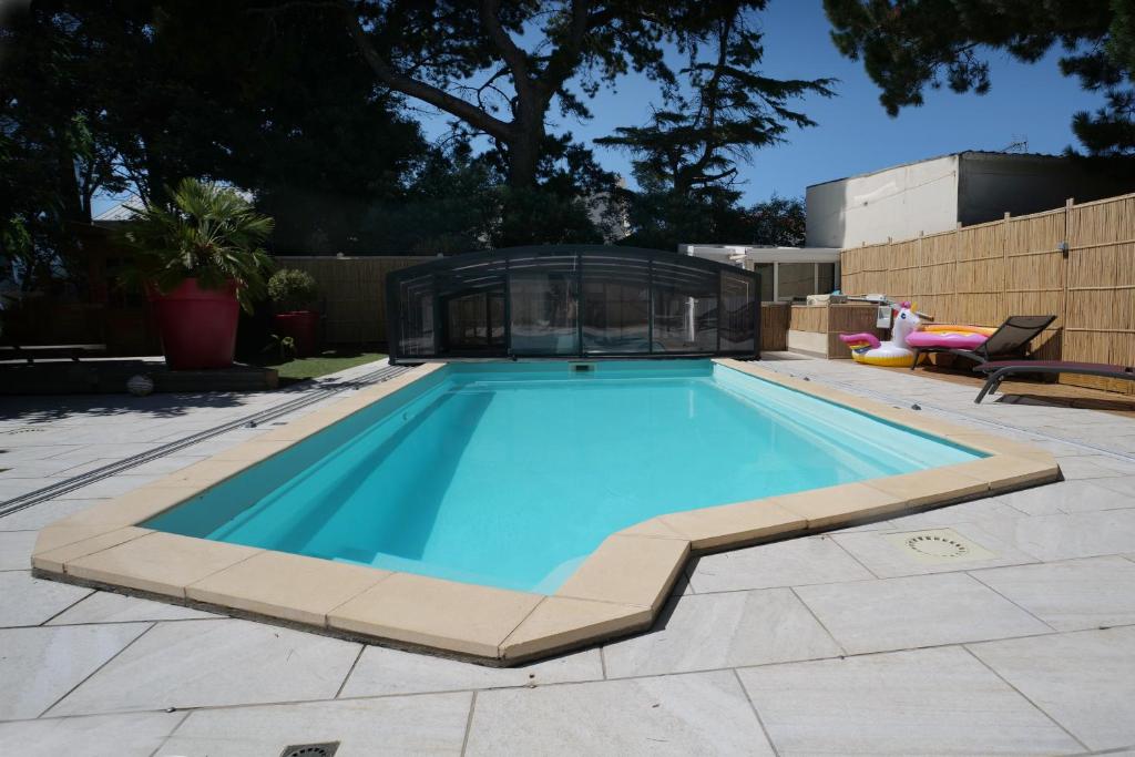 a swimming pool in a backyard with a glass house at Maison avec piscine 10 couchages in Pornichet