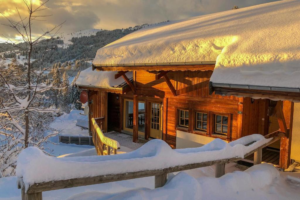 une cabane en rondins avec un toit recouvert de neige dans l'établissement Chalet Ruisseau, aux Gets