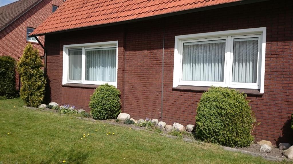a red brick house with two windows and bushes at Ferienwohnung Margarethe in Papenburg