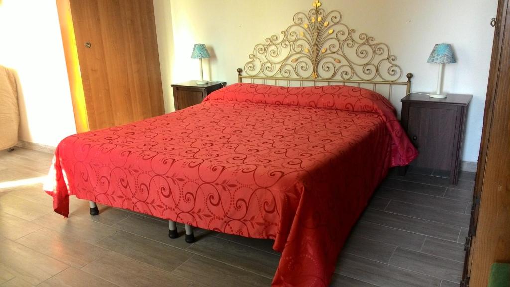 1 cama roja en una habitación con 2 lámparas en Appartamento Torrione, en Piani di Vallecrosia