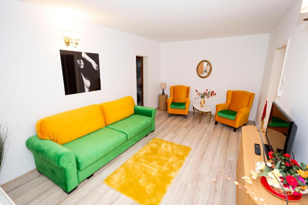 a living room with a green couch and two orange chairs at Apartament Maria in Galaţi
