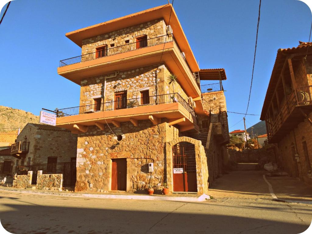 un gran edificio de piedra con balcón en una calle en Akrotainaritis Rooms, en Yerolimin
