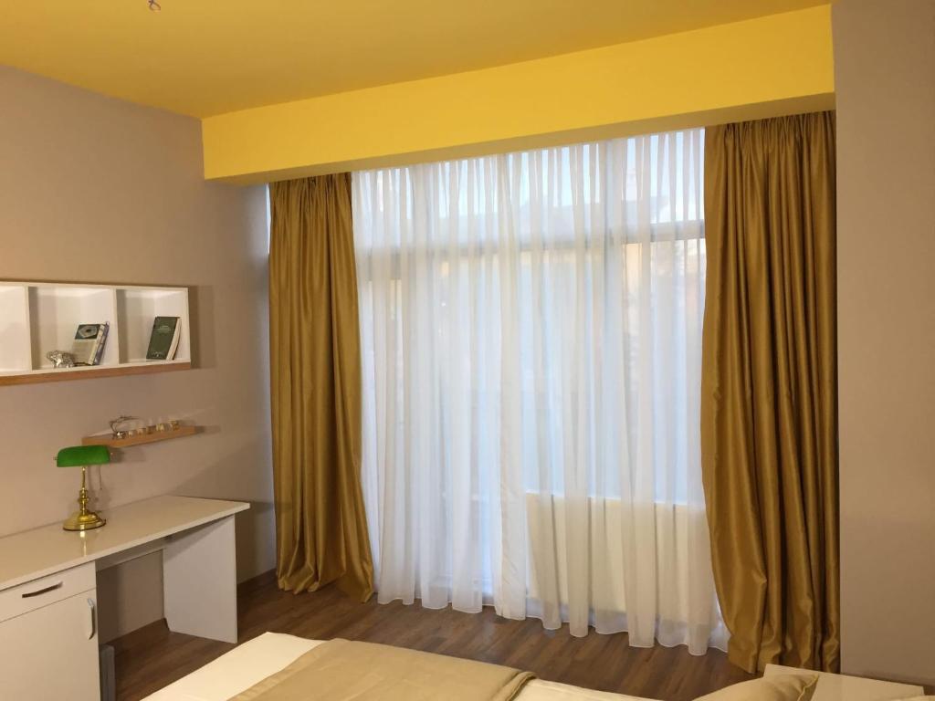 ein Schlafzimmer mit Fenster mit Vorhängen und einem Schreibtisch in der Unterkunft Dora Suit in Çankaya