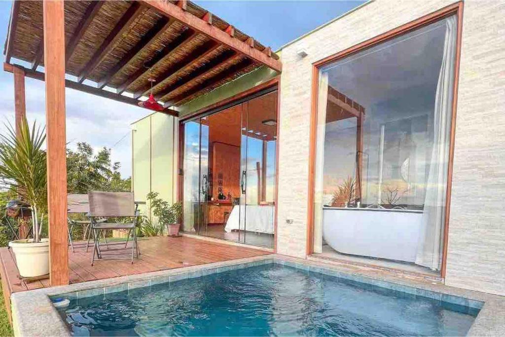 a house with a swimming pool and a patio at OKA VIVAH - Chalé Oka da Montanha in Jaboticatubas