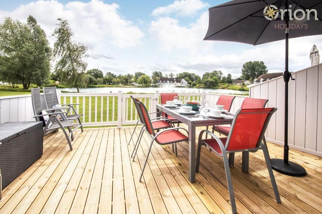 a deck with a table and chairs and an umbrella at Isis Lakes 40 - Casa Angela in South Cerney