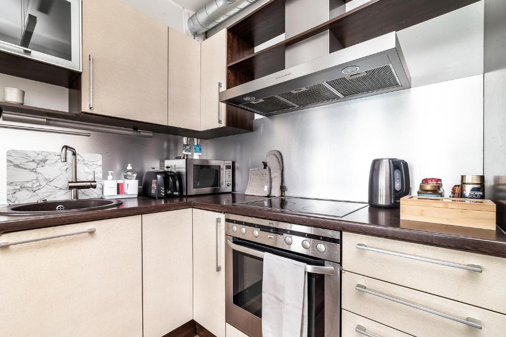 a kitchen with white cabinets and stainless steel appliances at Top floor near ferry terminal - free parking in Tallinn