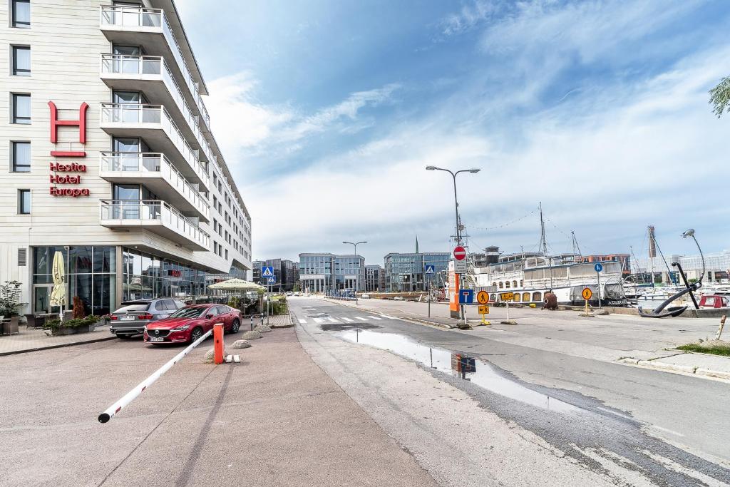 a street with a building and a red car on the street at Top floor near ferry terminal - free parking in Tallinn