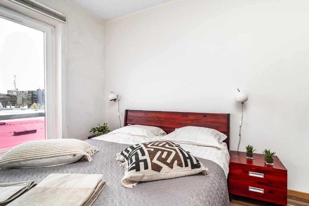 a bedroom with a bed with a wooden headboard and a window at Top floor near ferry terminal - free parking in Tallinn