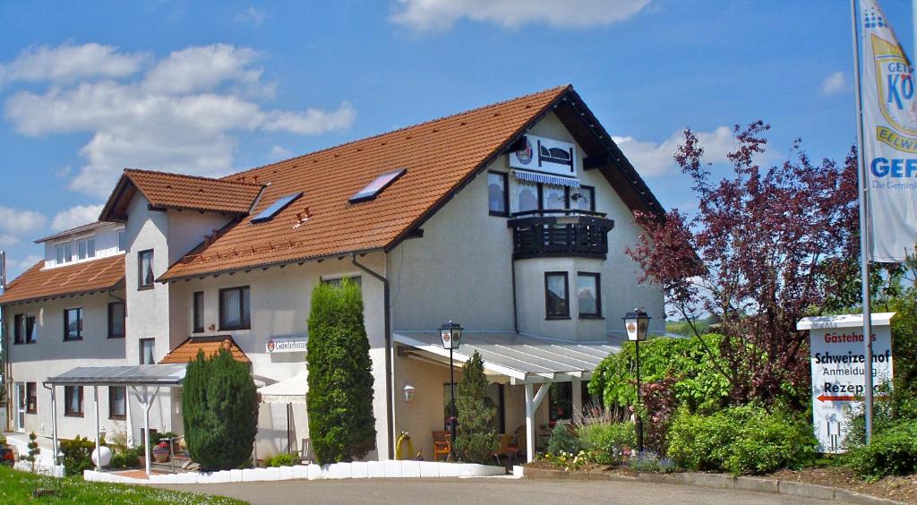 ein großes weißes Haus mit rotem Dach in der Unterkunft Gästehaus Schweizerhof in Böbingen an der Rems