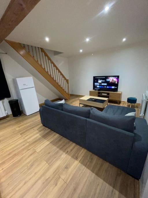 Una sala de estar con un sofá azul y un televisor. en Maison du Tripot, en Ligny-en-Barrois