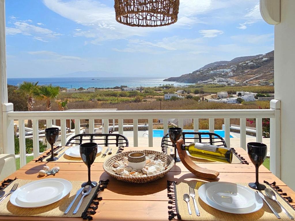 a wooden table with plates and utensils on a balcony at Mykonos4Islands Seaside Villas and Suites in Kalo Livadi