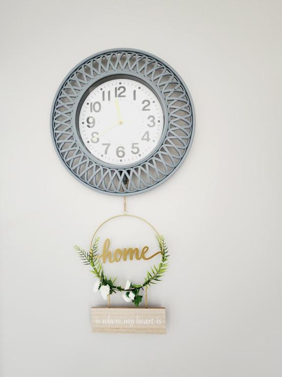 Un reloj colgado en una pared con un cartel de casa. en Blue Button, en Pretoria