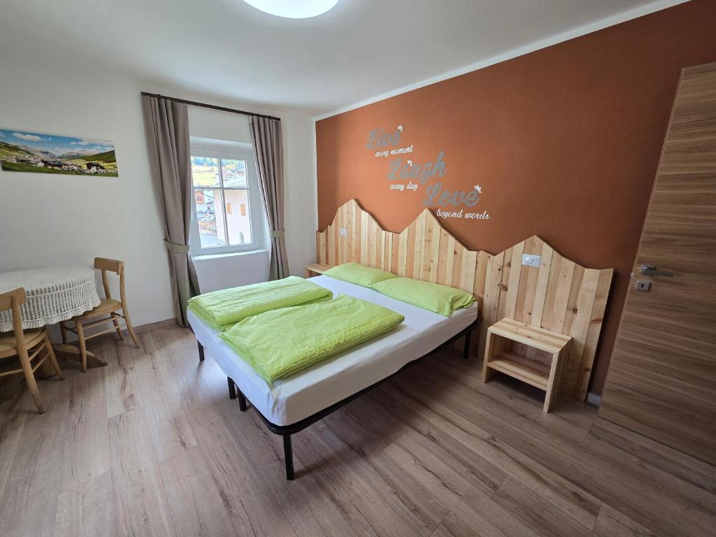 a bedroom with a bed with green sheets and a table at Appartamenti GG - Big and central in Livigno