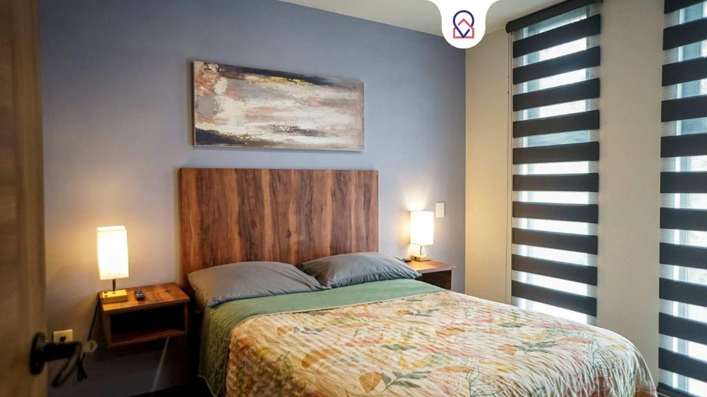 a bedroom with a bed with two night stands and two lamps at Modern 1BR apartment with Smart Access & Parking in San Luis Potosí