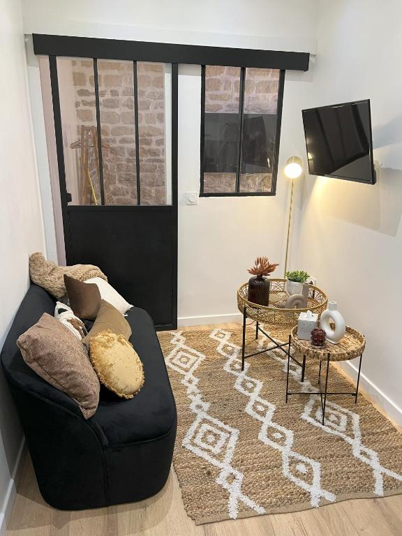 un salon avec un canapé noir et une table dans l'établissement Paris Secret Spot - Loft Unique aux portes de Paris, à Gentilly