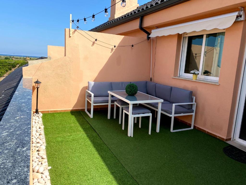 a patio with green grass and a table and chairs at Duplex Torre la Sal Magic World La Tormesilla in La Estación