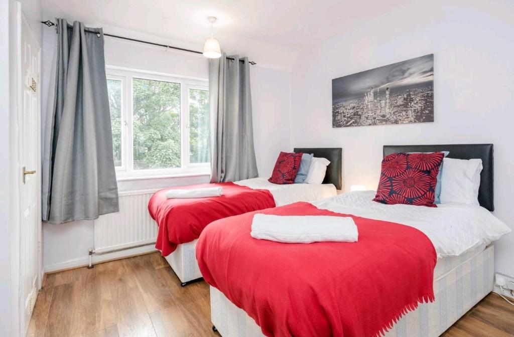 two beds in a room with red blankets at Everything You Need I Super Comfy I Sleeps 7 I WiFi I Parking I 4BDR in Dagenham