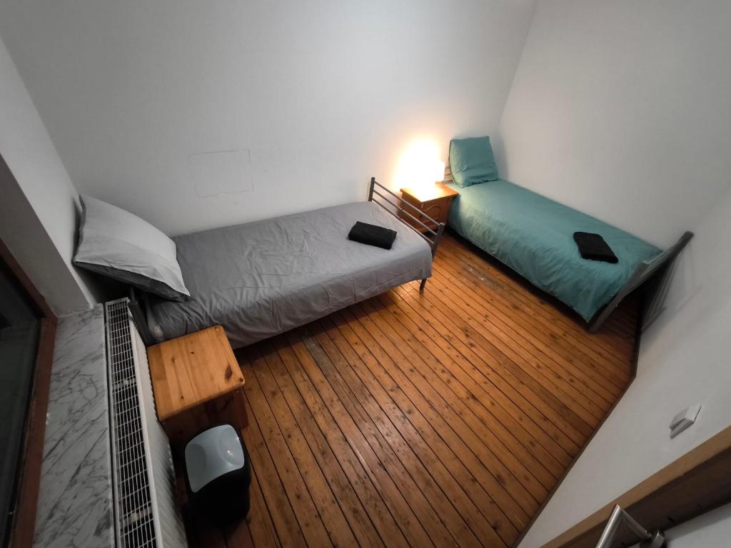 a bedroom with two beds and a wooden floor at Maison entière privée in Charleroi