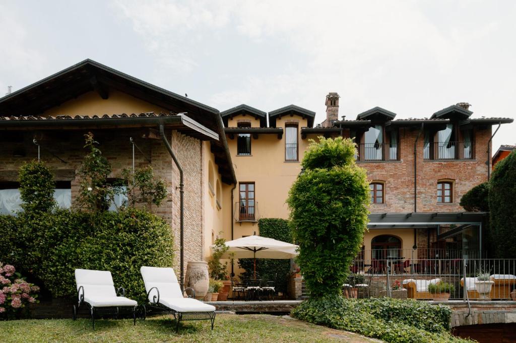 una casa con due sedie e un ombrellone davanti di Hotel Casa Pavesi a Grinzane Cavour
