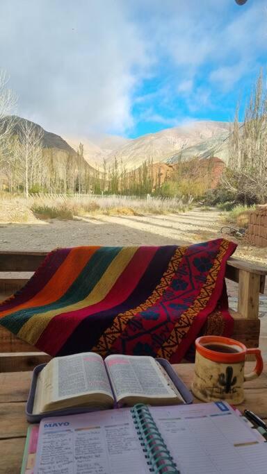a table with two books and a coffee mug and a blanket at Cabaña la Viña in Purmamarca