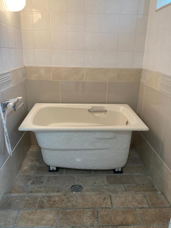 e bagno con vasca e pavimento piastrellato. di Haryugetu Guesthouse in NASA a Kaiyo
