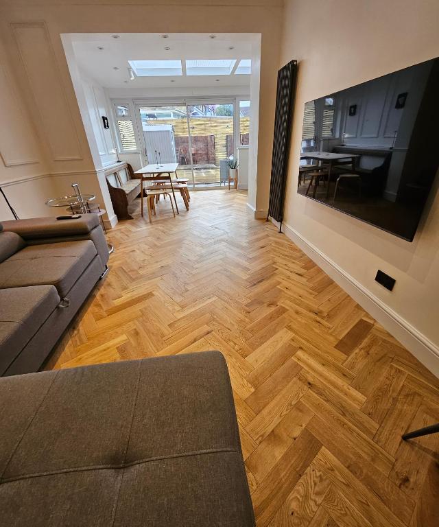a living room with a couch and a television on a wall at Wembley London lovely 6 bed House sleeps up to 14 in London