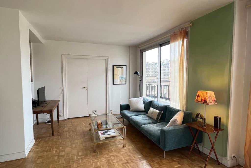 un salon avec un canapé vert et une table dans l'établissement Vaste appt baigné de lumière, à Paris