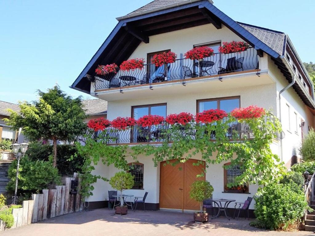 a house with red flowers on the balconies at Marmann - large holiday apartment in Osann-Monzel