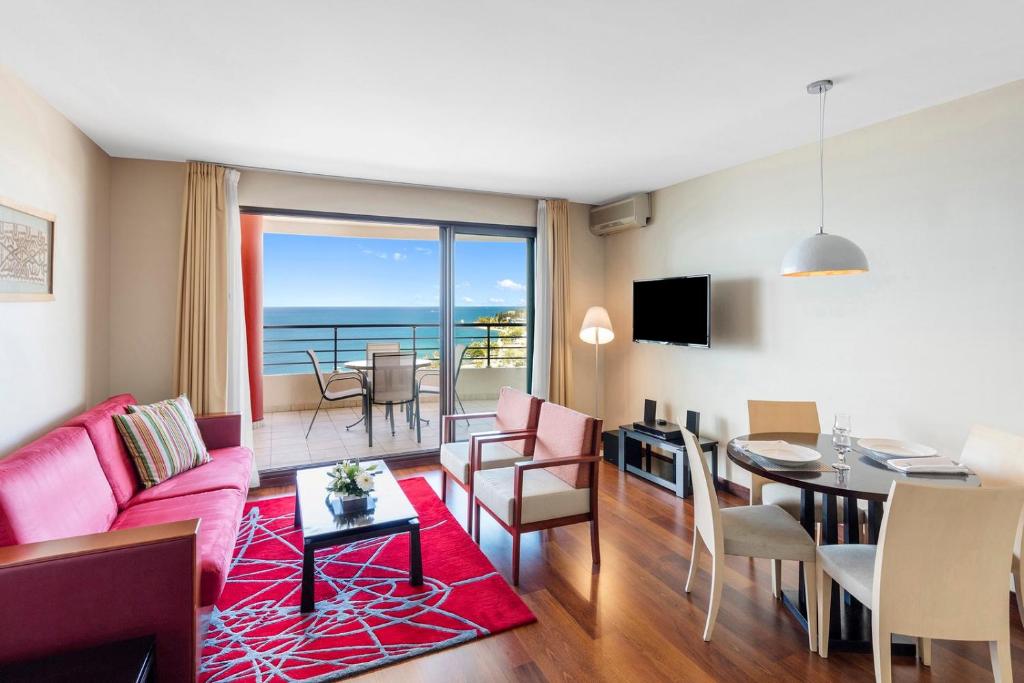 un soggiorno con divano rosa e una sala da pranzo di Ramada Hotel & Suites by Wyndham Noumea a Noumea