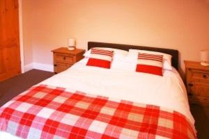 a bed with two red and white pillows on it at Bowl Full Holiday Let in Lincoln