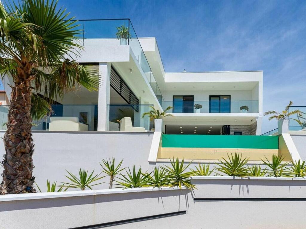 a house with a palm tree in front of it at Luxury Villa Michele with heated pool in Jasenice