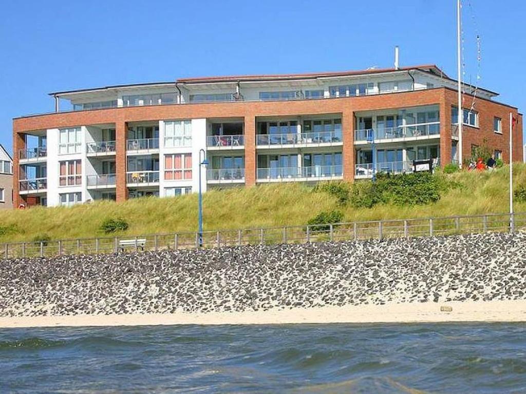 a building sitting on top of a beach next to the water at Kniepsand in the Amrumer Welle in Wittdün