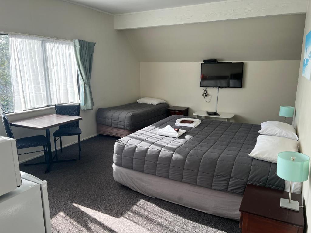 a hotel room with a bed and a table and a desk at Drury Motor Lodge in Drury