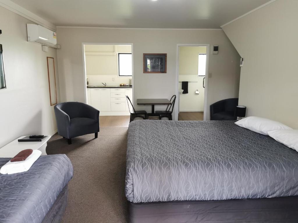 a bedroom with a bed and a chair and a table at Drury Motor Lodge in Drury