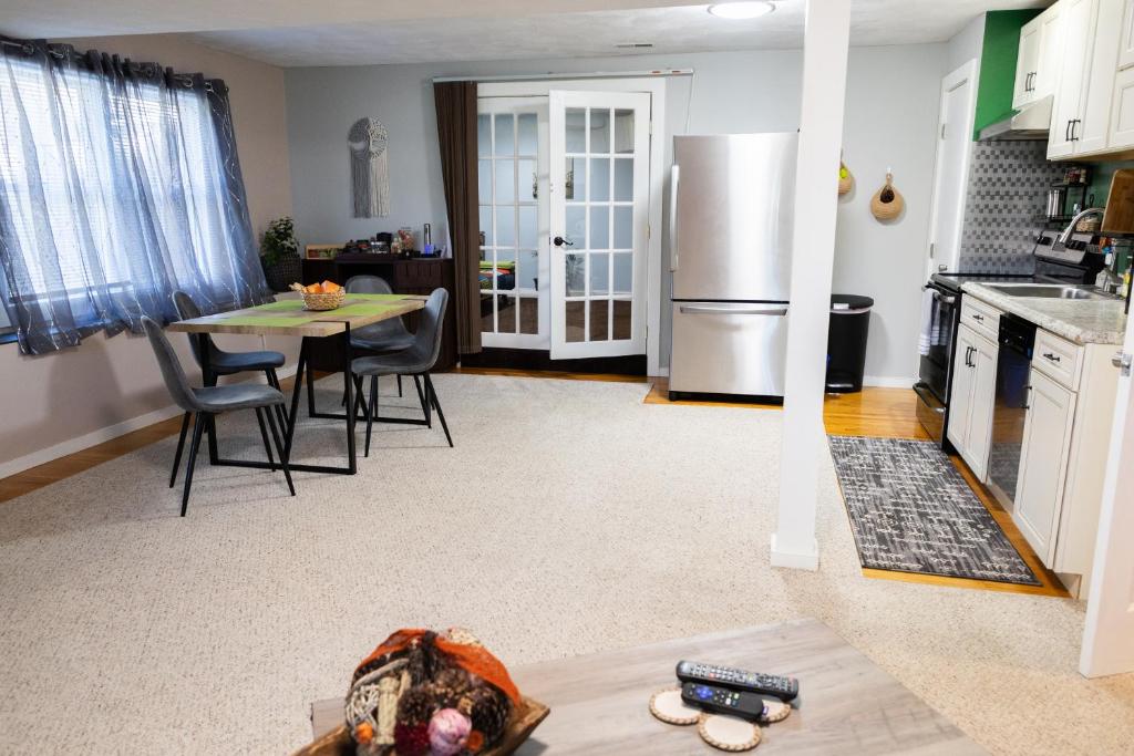 a kitchen with a table and a stainless steel refrigerator at Cosy and Charming 2-bedroom apartment in Woburn