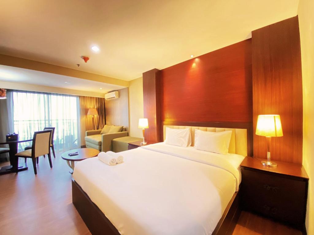 a hotel room with a large bed and a desk at Fancy and Nice Studio at El Royale Apartment By Travelio in Bandung