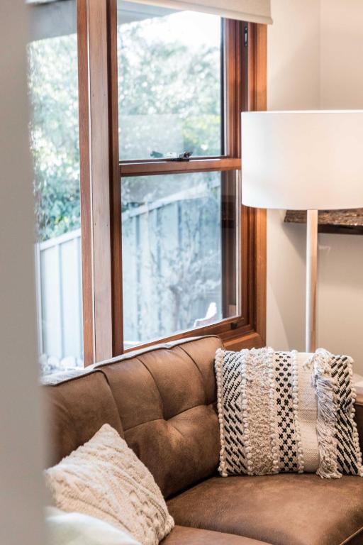 a brown couch sitting in front of a window at Porepunkah Cottage in Porepunkah