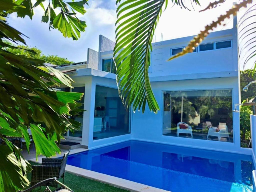 una casa azul con piscina y palmeras en Playa, en Playa del Carmen