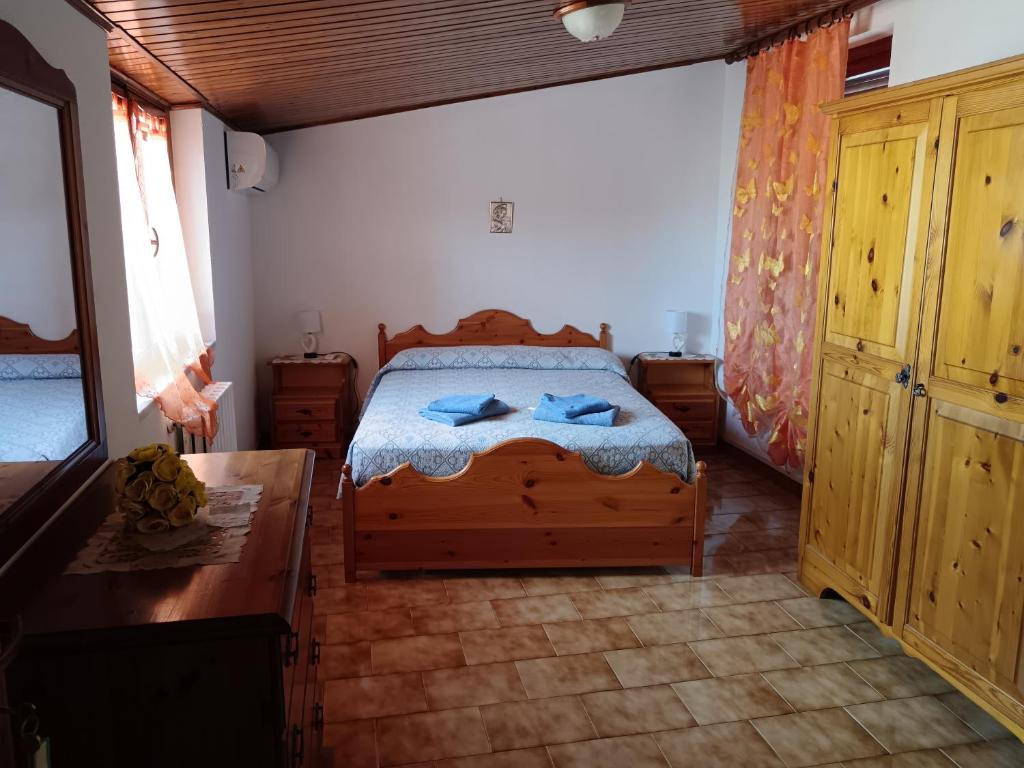 una camera con letto in legno e cassettiera in legno di Affittacamere S' Eremu a Dorgali