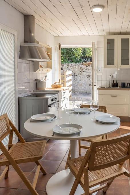 Il dispose d'une cuisine avec une table et des chaises blanches. dans l'établissement Maison au coeur du Croisic idéalement placée !, au Croisic