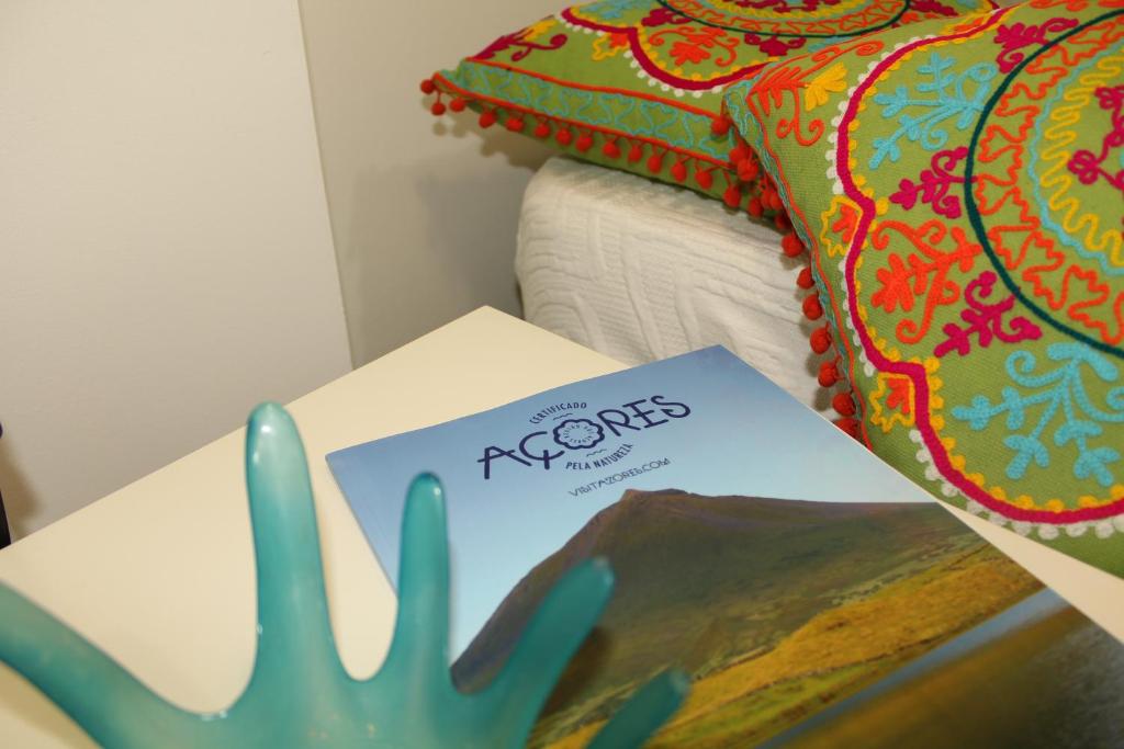 una mesa con un libro al lado de una cama en Costa Apartments, en Ponta Delgada