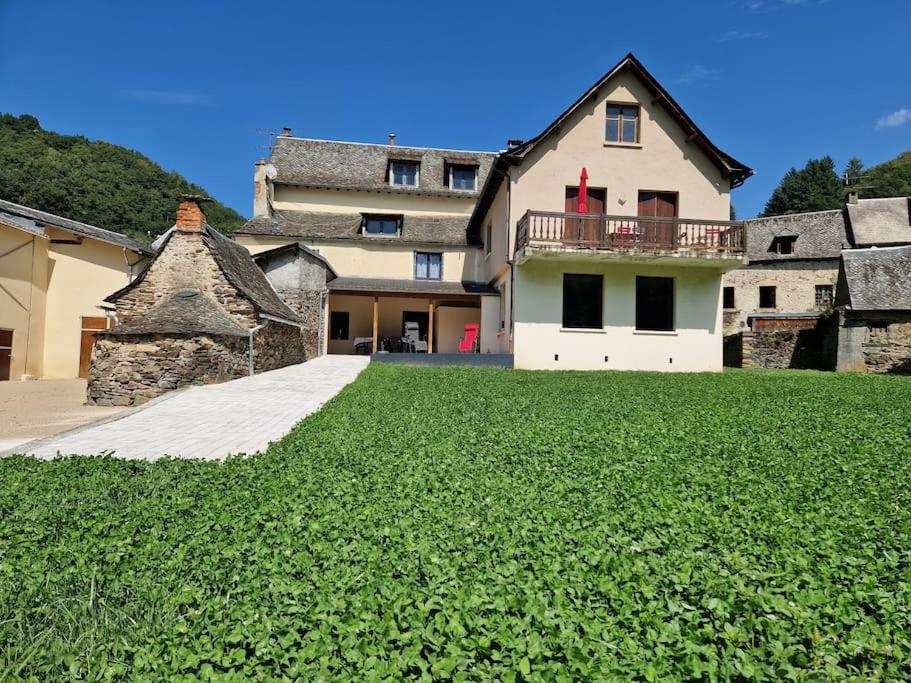 a large house with a grass yard in front of it at Maison Vidal, au pied de l'Aubrac in Coubisou