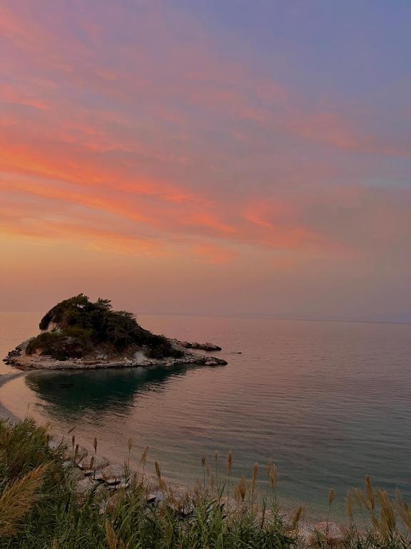 a small island in the ocean with a sunset at Sunrise in Kokkari